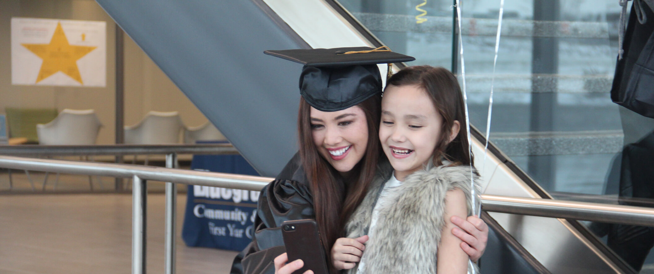 mom in grad outfit taking selfie with daughter