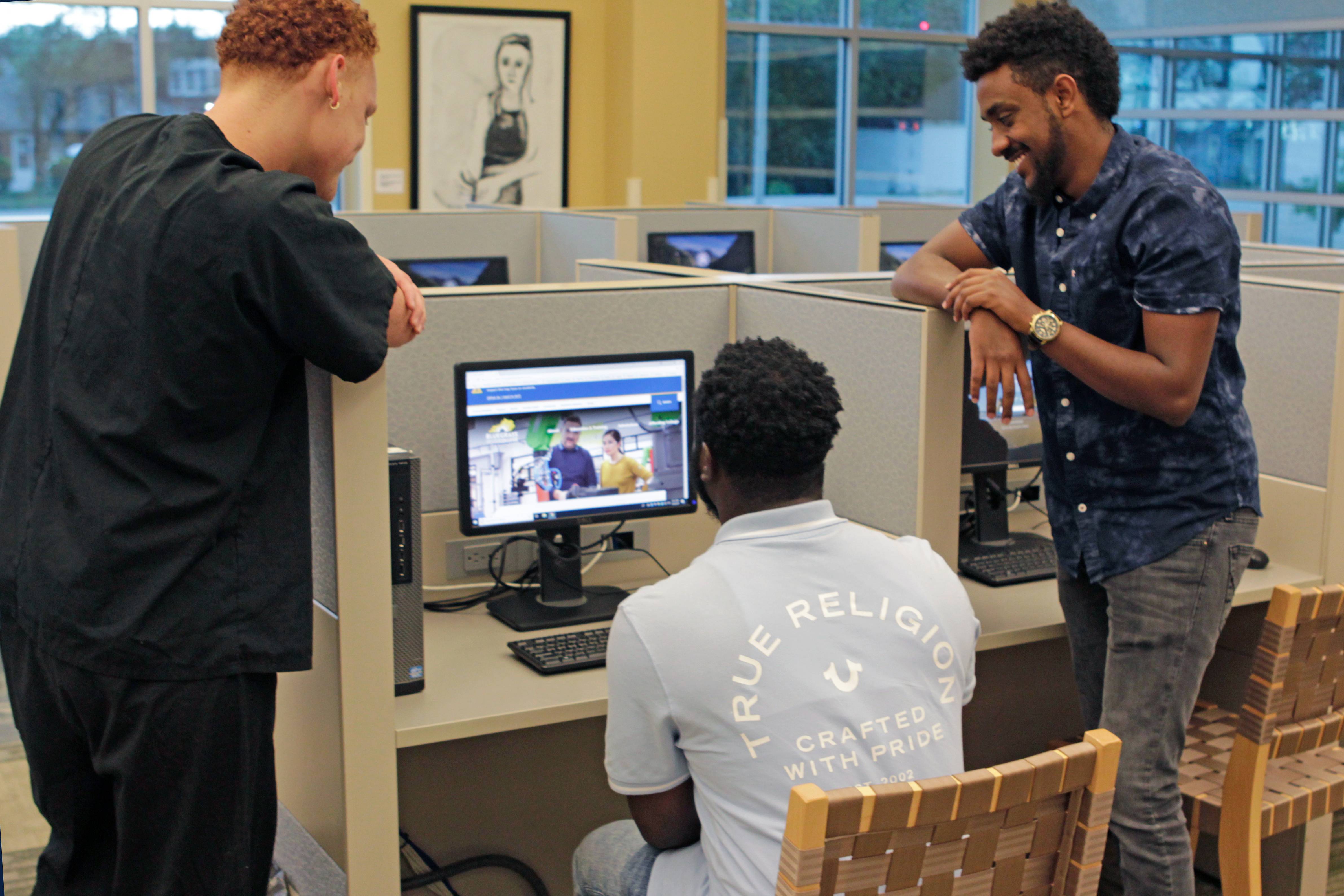 3 students looking at a computer monitor