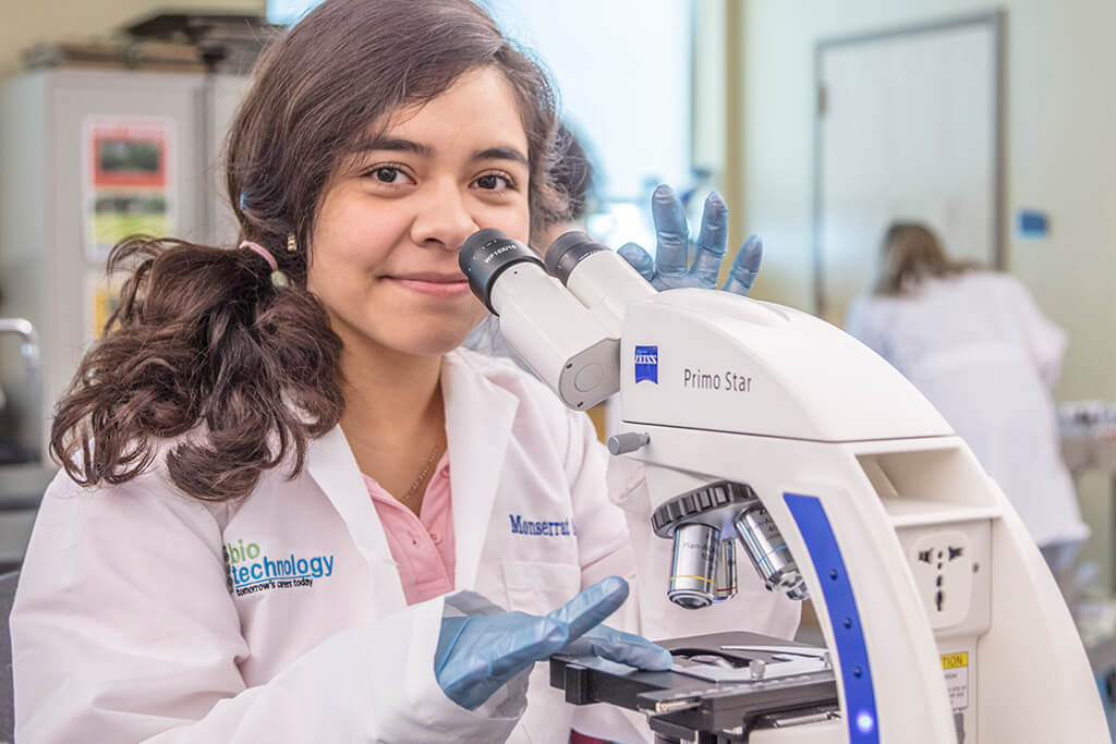 female student in lab with microscope