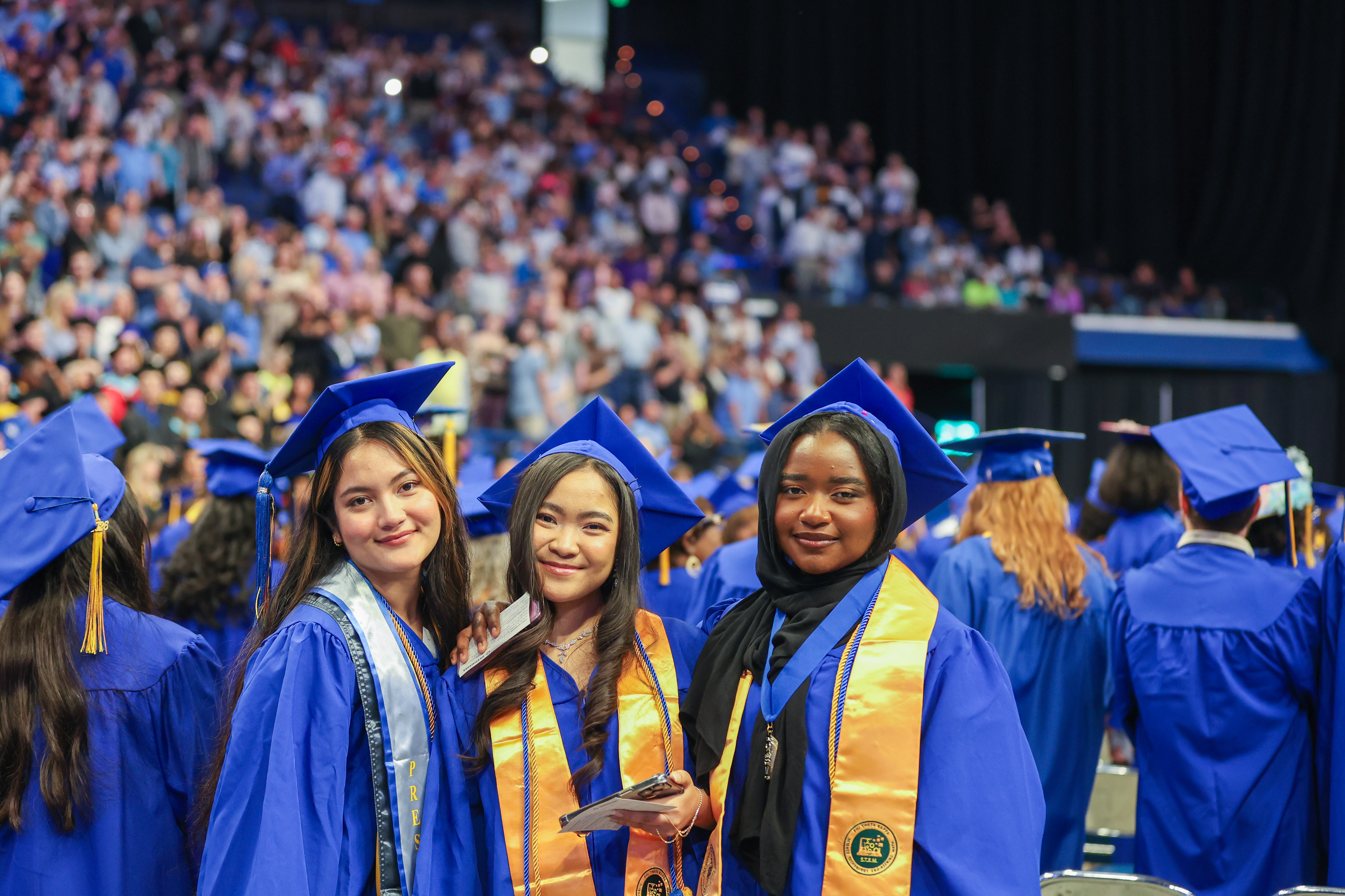 three graduates stand together smiling