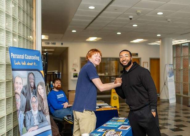 two students smiling while shaking hands