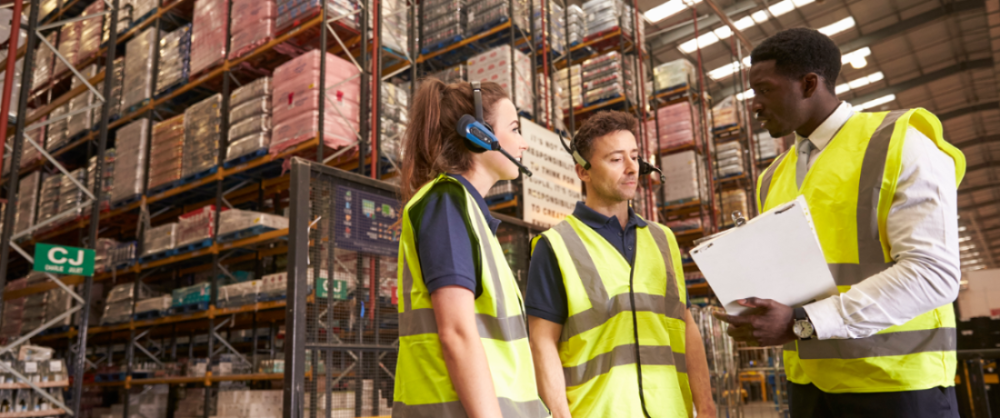 workers in high-visibility vests in warehouse having discussion in warehouse