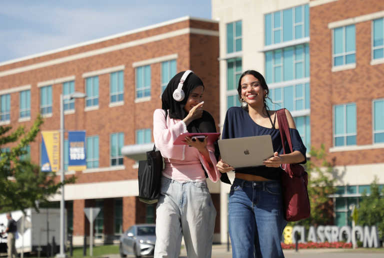 two students walking together smiling