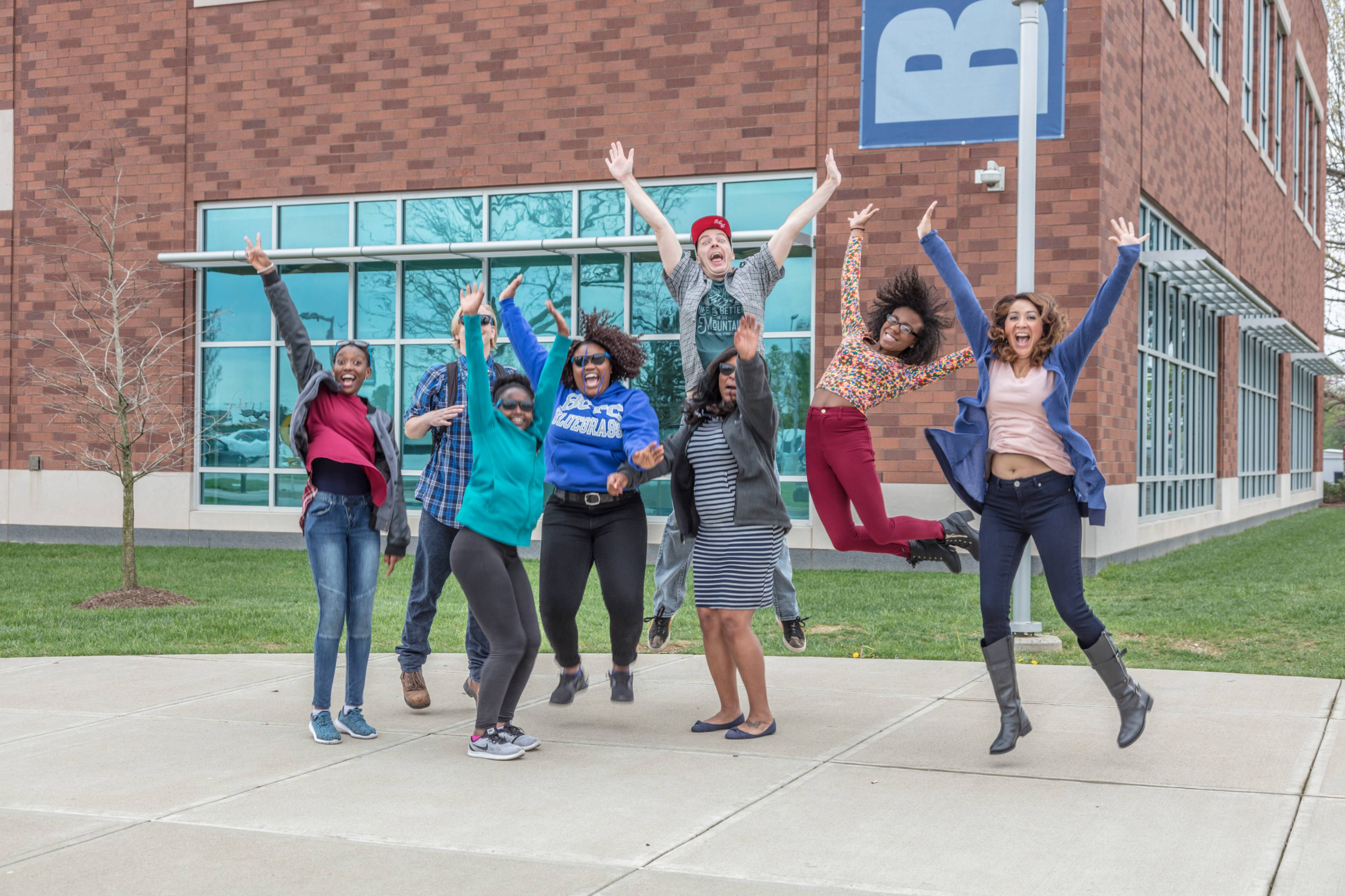 students jumping in front of building on campus
