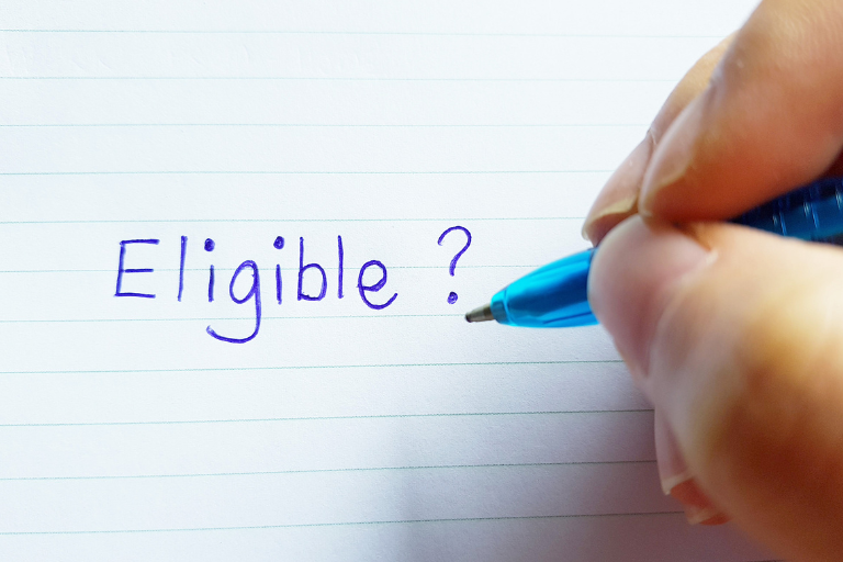 a hand writing the word eligible on a piece of paper