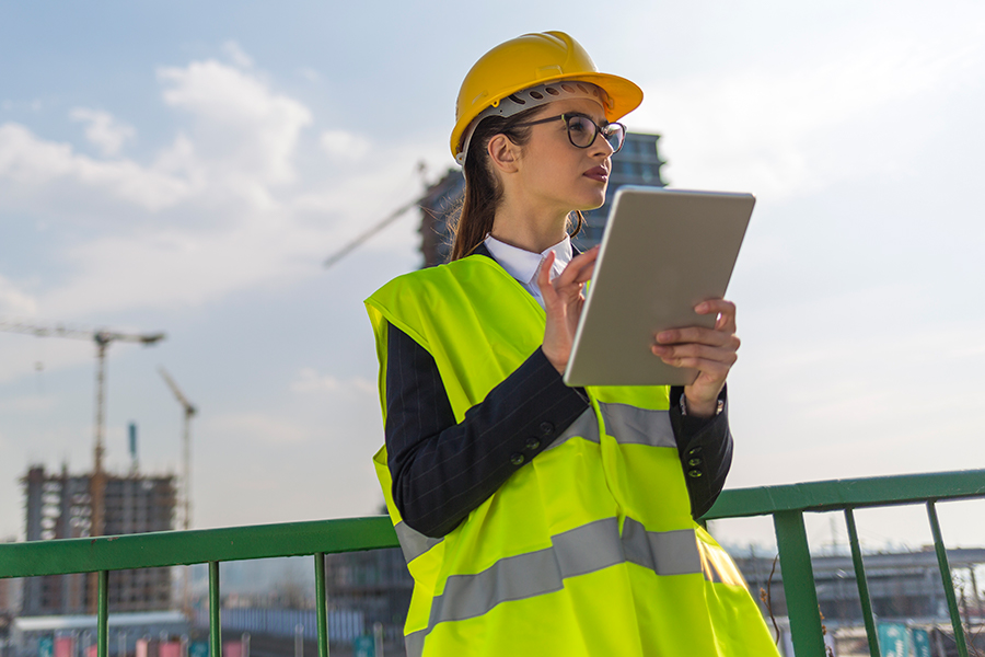 person in hard hat and vest checking tablet