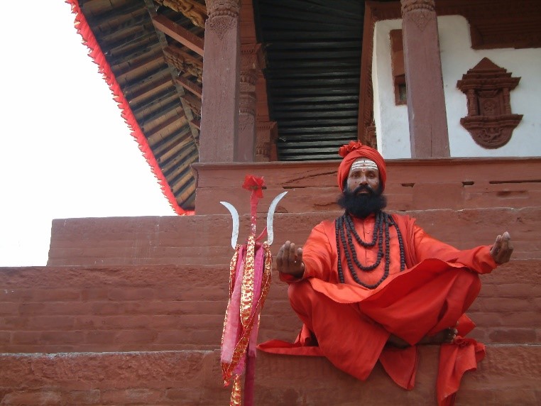 Man dressed in red sits on the steps of a temple