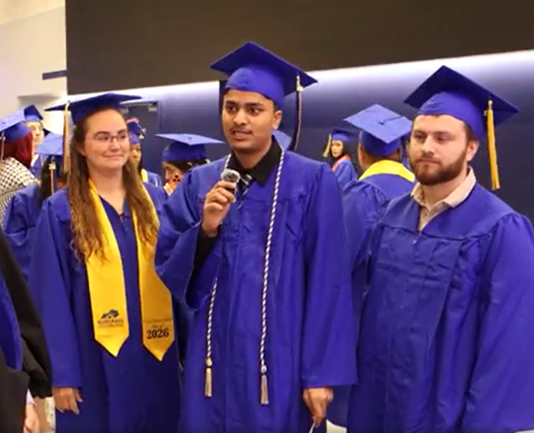 three people stand together in graduation garb