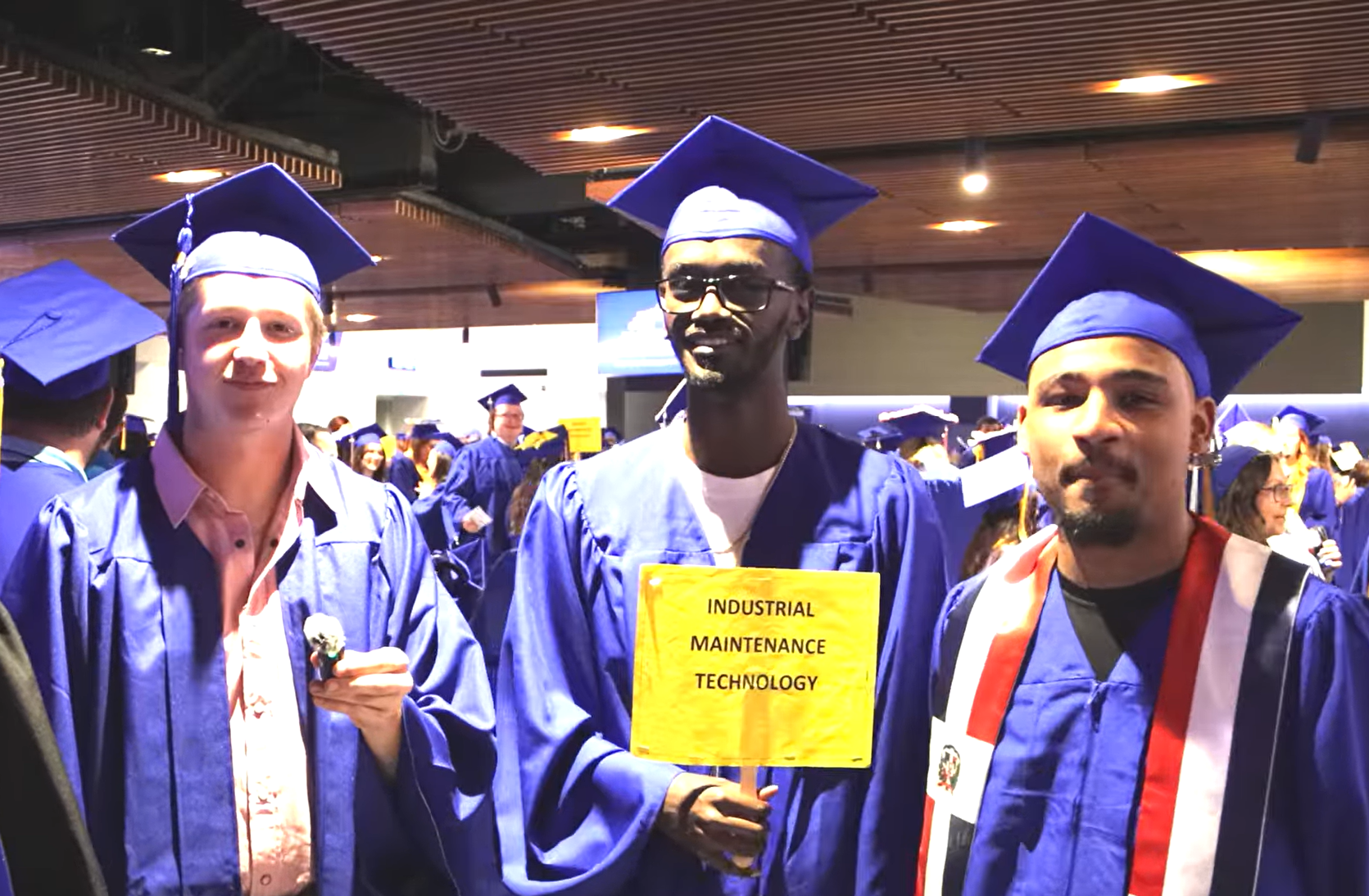 three people stand together wearing graduation garb
