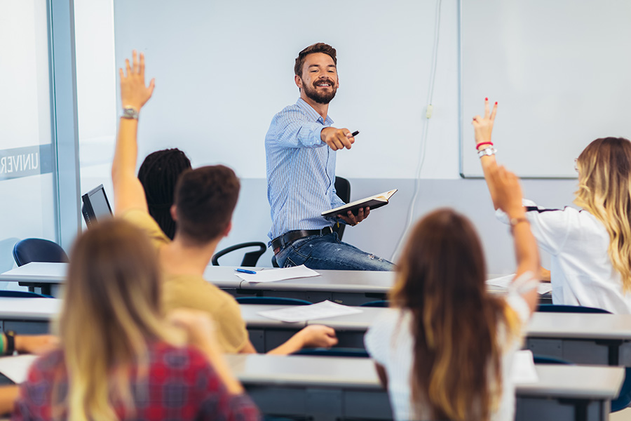 teacher in classroom with students raising hands