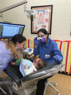 dental hygienists examining a young child's teeth