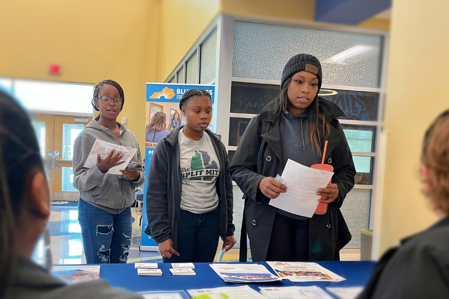 Students standing in front of table with information handouts