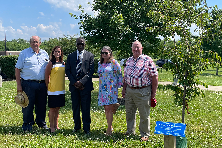 Mayor Ed Burtner, Cindy Banks, Dr. Koffi Akakpo, Roni-Anne Denham, and Ron Tierney standing by tree planted on Winchester Campus to remember Todd Denham.