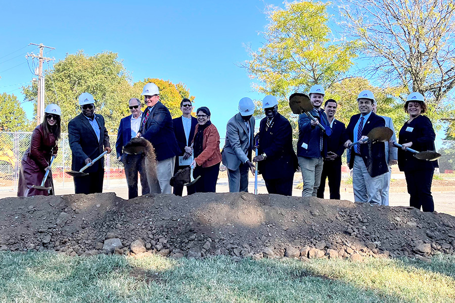 Dr. Akakpo with city officials, state officials, and student speakers side-by side in hard hats, shoveling dirt