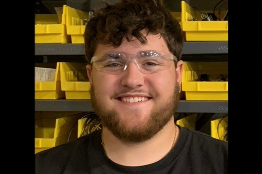 Elijah Patterson wearing protective eyewear in front of parts shelves