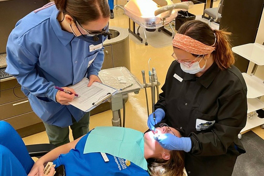 BCTC Dental Students cleaning a patient's teeth under teacher supervision